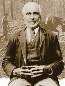 senior man seated facing camera holding what is likely a bible with two hands at his lap