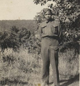 b&w young man standing hands behind back in military uniform
