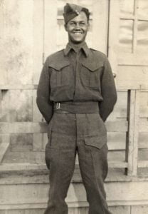 b&w photo of young man standing hands behind back in military uniform