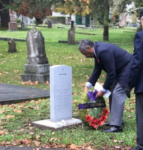 man places wreath at gravemarker