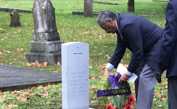 man places wreath at gravemarker