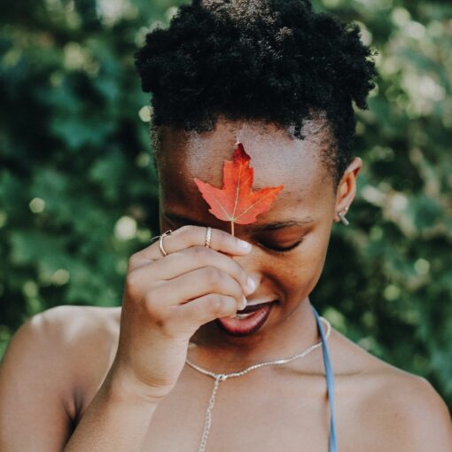 black woman holding maple leaf at forehead