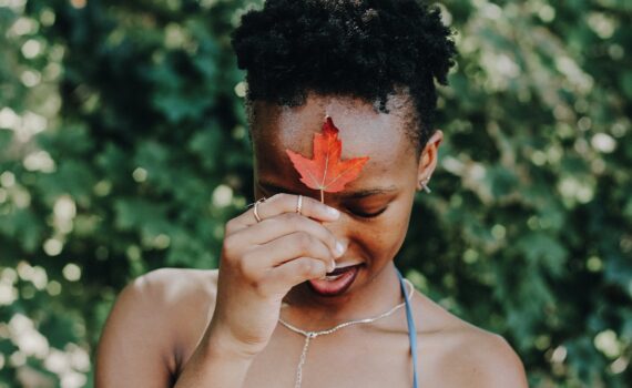 black woman holding maple leaf at forehead