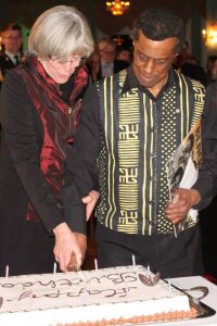 man and woman standing together cutting birthday cake