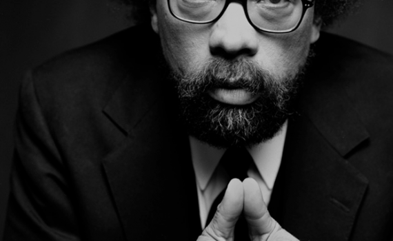 b&w portrait, black man wearing glasses, suit and tie looking directly at camera, hands together in front