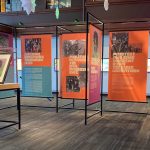 exhibition area with information panels, light boxes on walls, art in display case