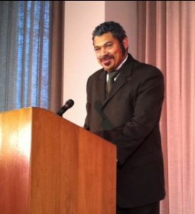 justin carter, suit & beard standing at podium portraying Mifflin Gibbs