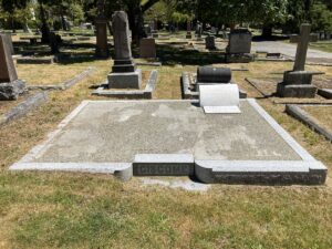 Large white marble curbed plot, plot is paved, bright white marble head stone and flat plaque at top right