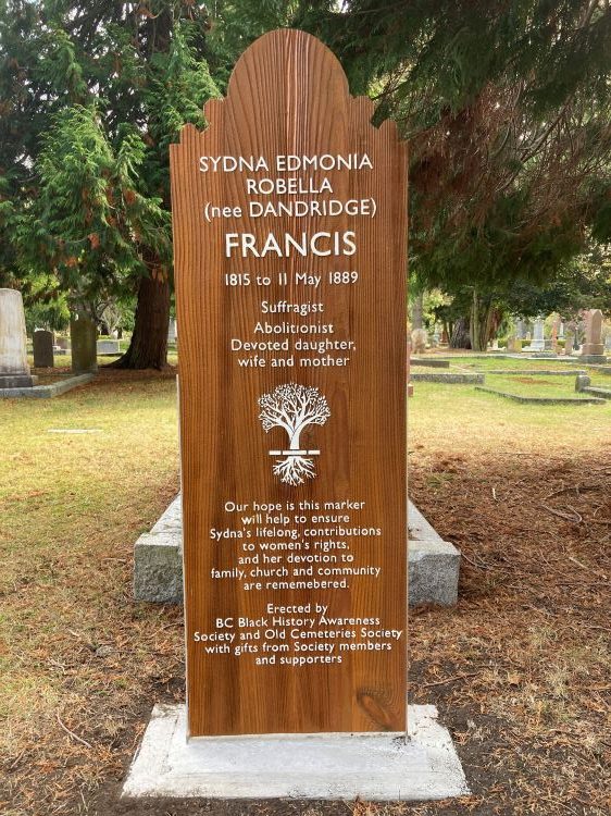 medium-colored wooden-stained grave marker with white lettering, carved tree outline in white is centred
