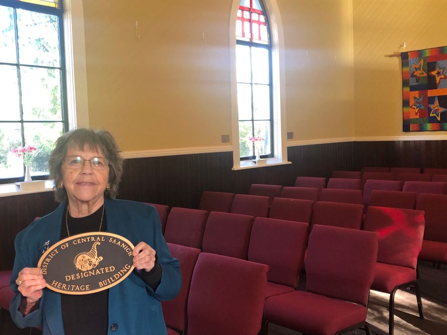 woman on the left of the picture holding plaque - rows of seating seen to the right