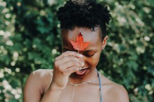 black woman holding maple leaf at forehead
