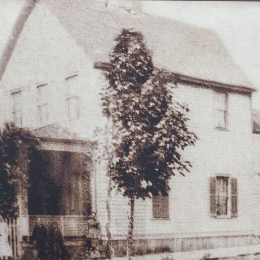 sepia toned taken from side angle of 2 story shingled and gabled house with porch, fence and trees at front house