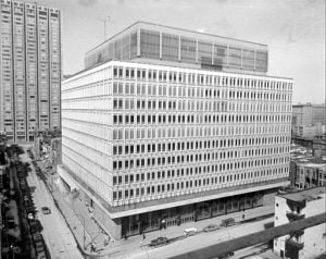 gray-toned image of 11 story concrete building with prominent windows in city-scape