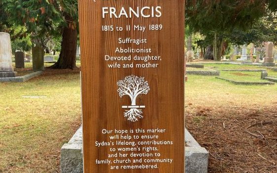 medium-colored wooden-stained grave marker with white lettering, carved tree outline in white is centred